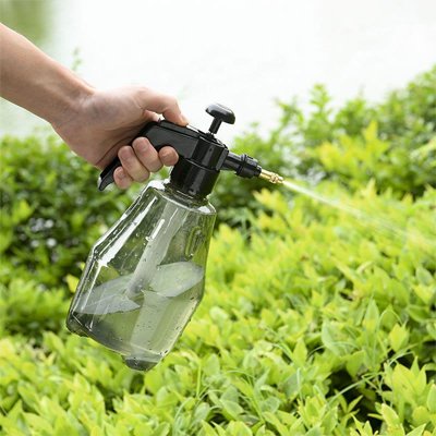 Pulverisateur professionel gris arrosant plantes vertes avec jet directionnel