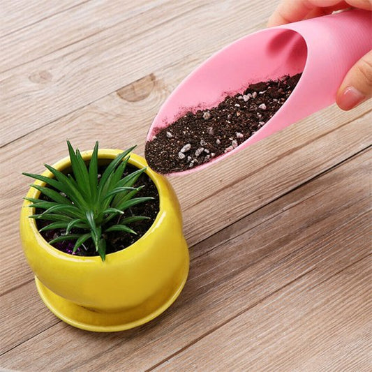 personne qui apporte de la terre par la petite pelle jardin à une plante à petit pot