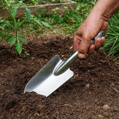 petite pelle de jardin planter dans le sol tenu par une main dans un jardin