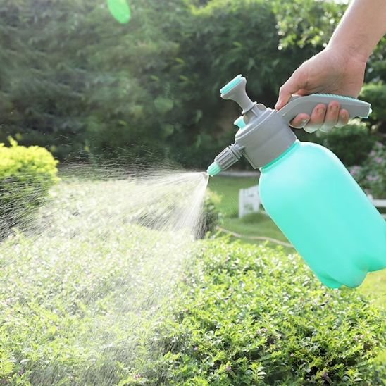 une personne qui utilise le pulverisateur jardin pour sa haie